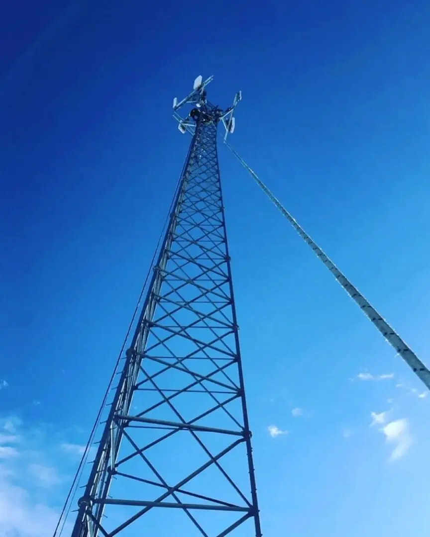 A mobile tower with antennas and a steel wire attached